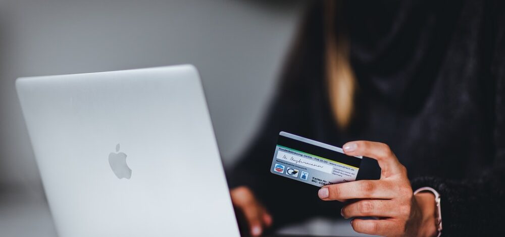 woman holding black smartphone near silver macbook