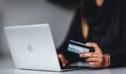 woman holding black smartphone near silver macbook