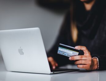 woman holding black smartphone near silver macbook