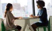two women sitting beside table and talking
