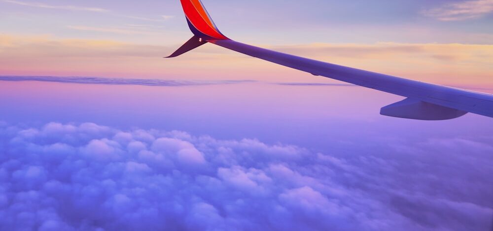 person in a plane flying at high altitude taking photo of left airplane wing during daytime